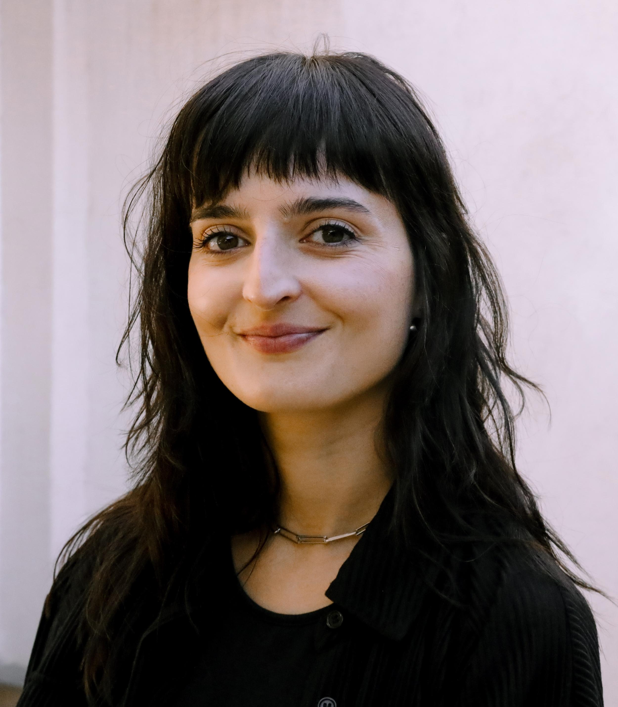 Lola Porto, smiling, photographed against a pale wall.