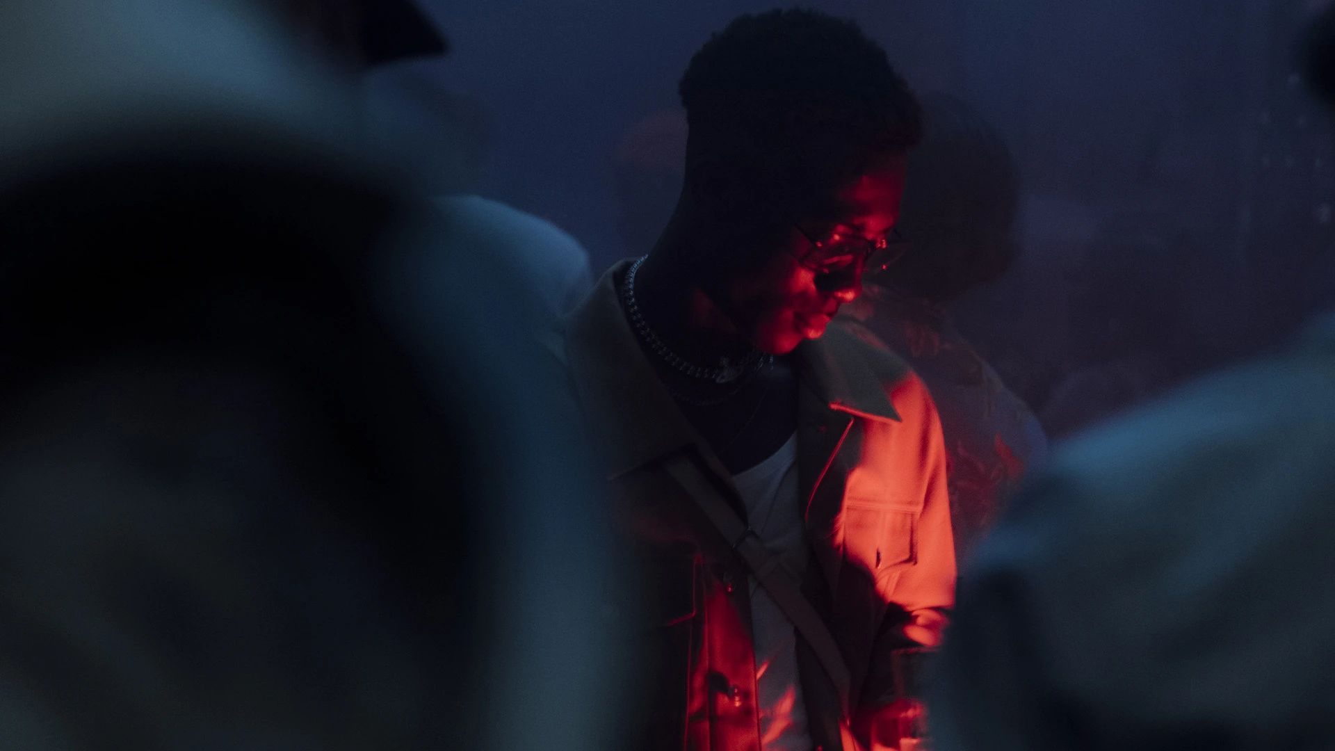A guest in a pale jacket lit red against a blue-dark crowd.