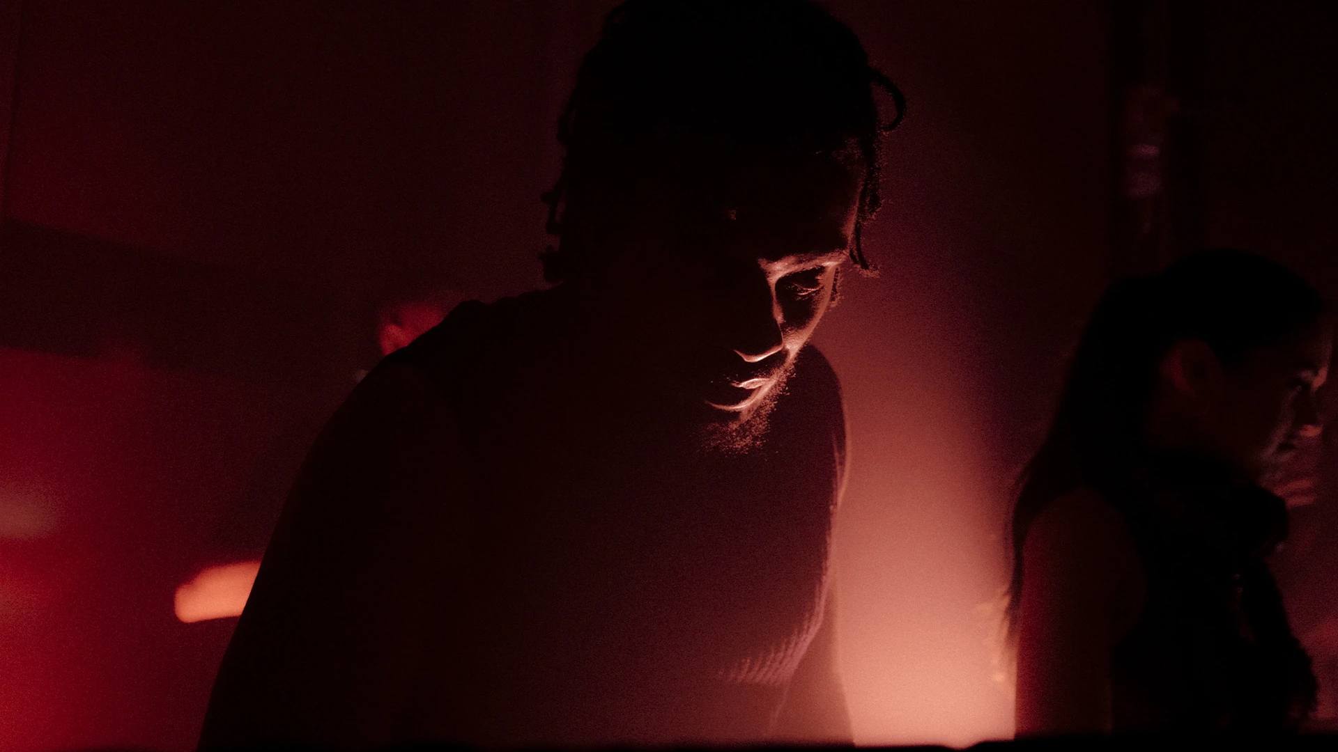A silhouetted figure at the decks against deep red light.