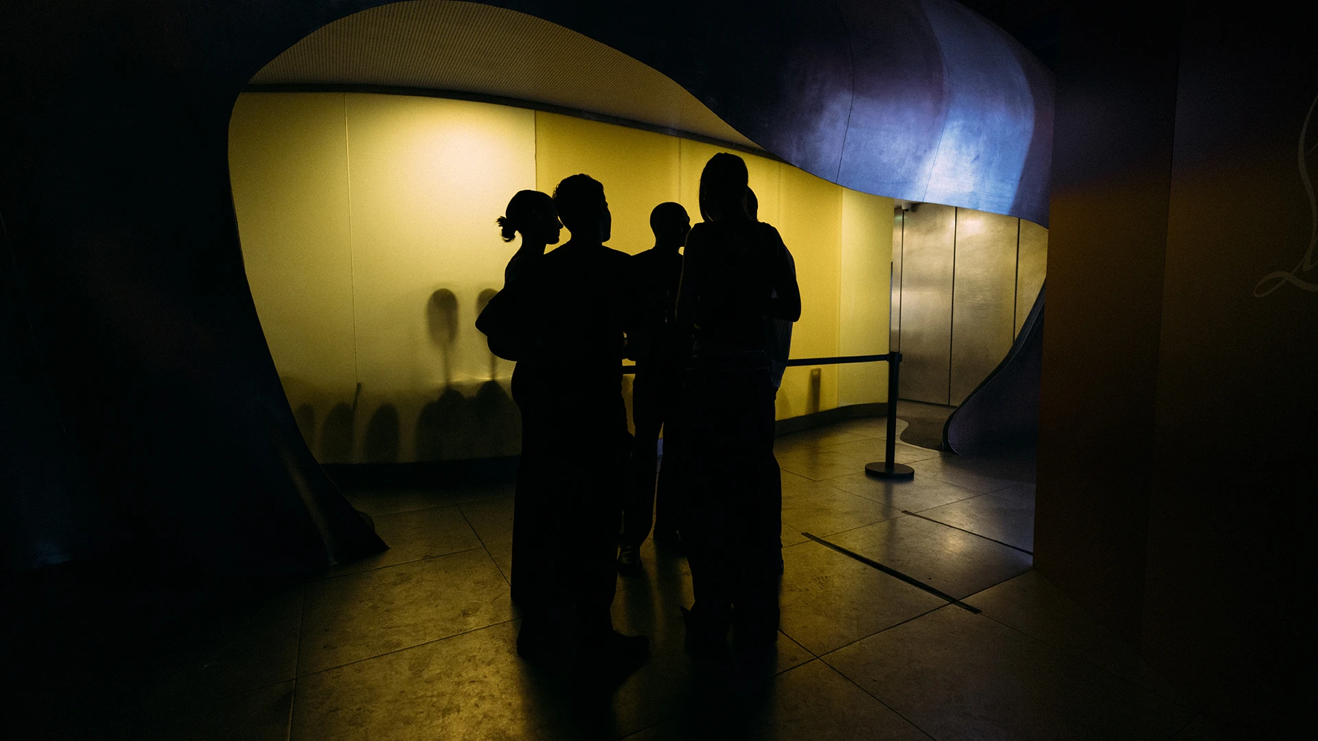 Guests silhouetted against a lit alcove in a darkened corridor.