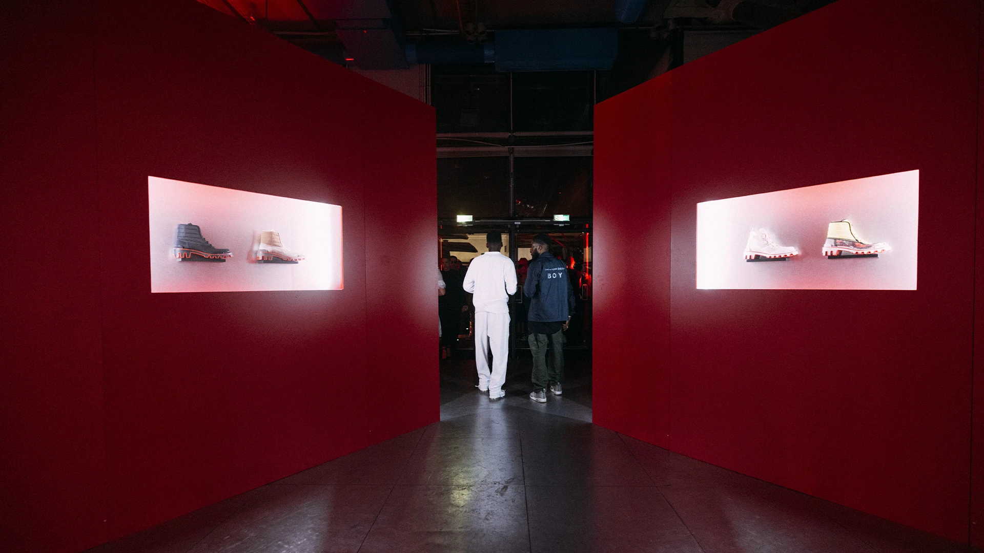 A red-walled corridor with Louboutin shoes displayed in backlit recesses.