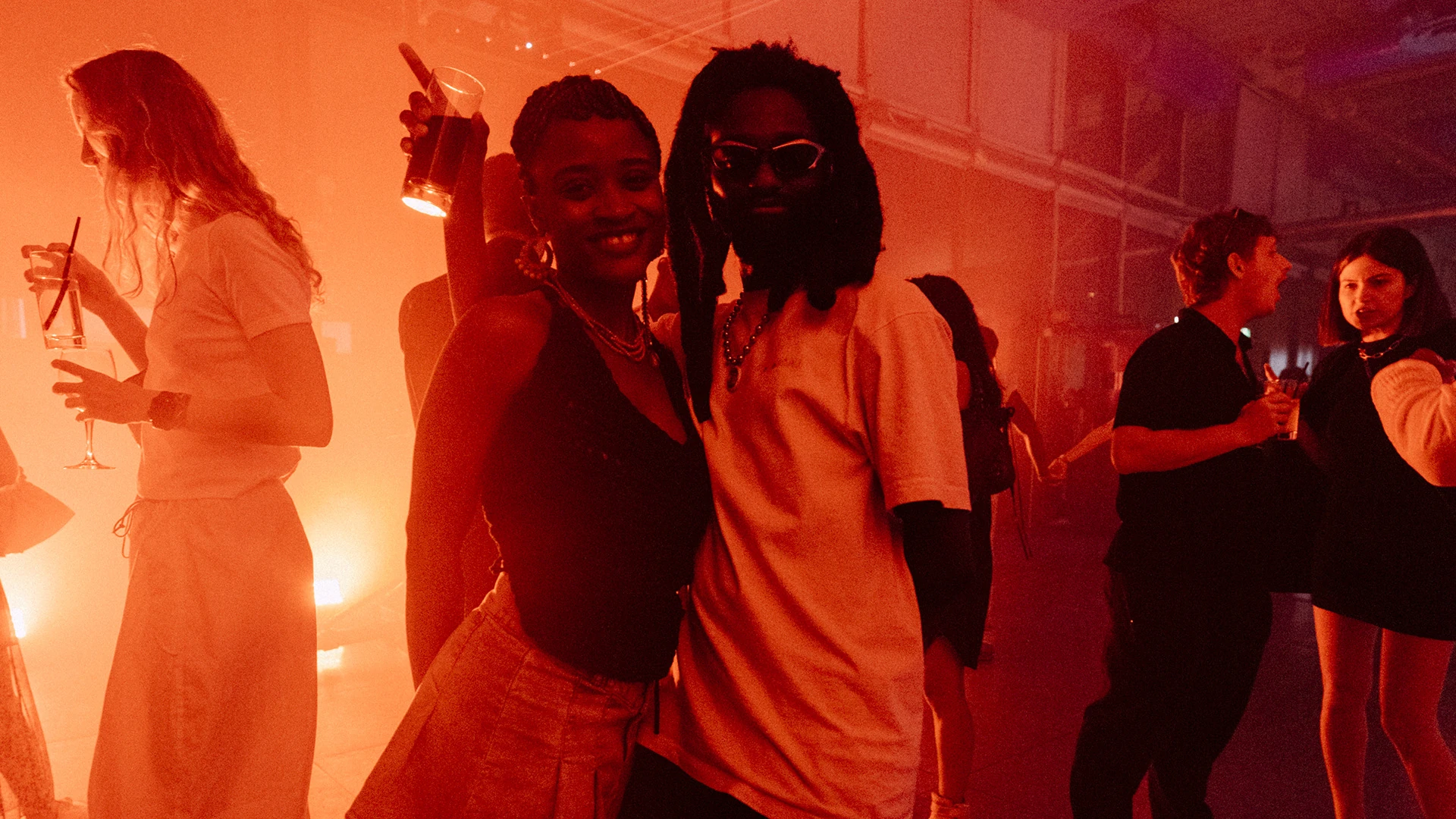 Two guests dancing and smiling in a room saturated with orange light.