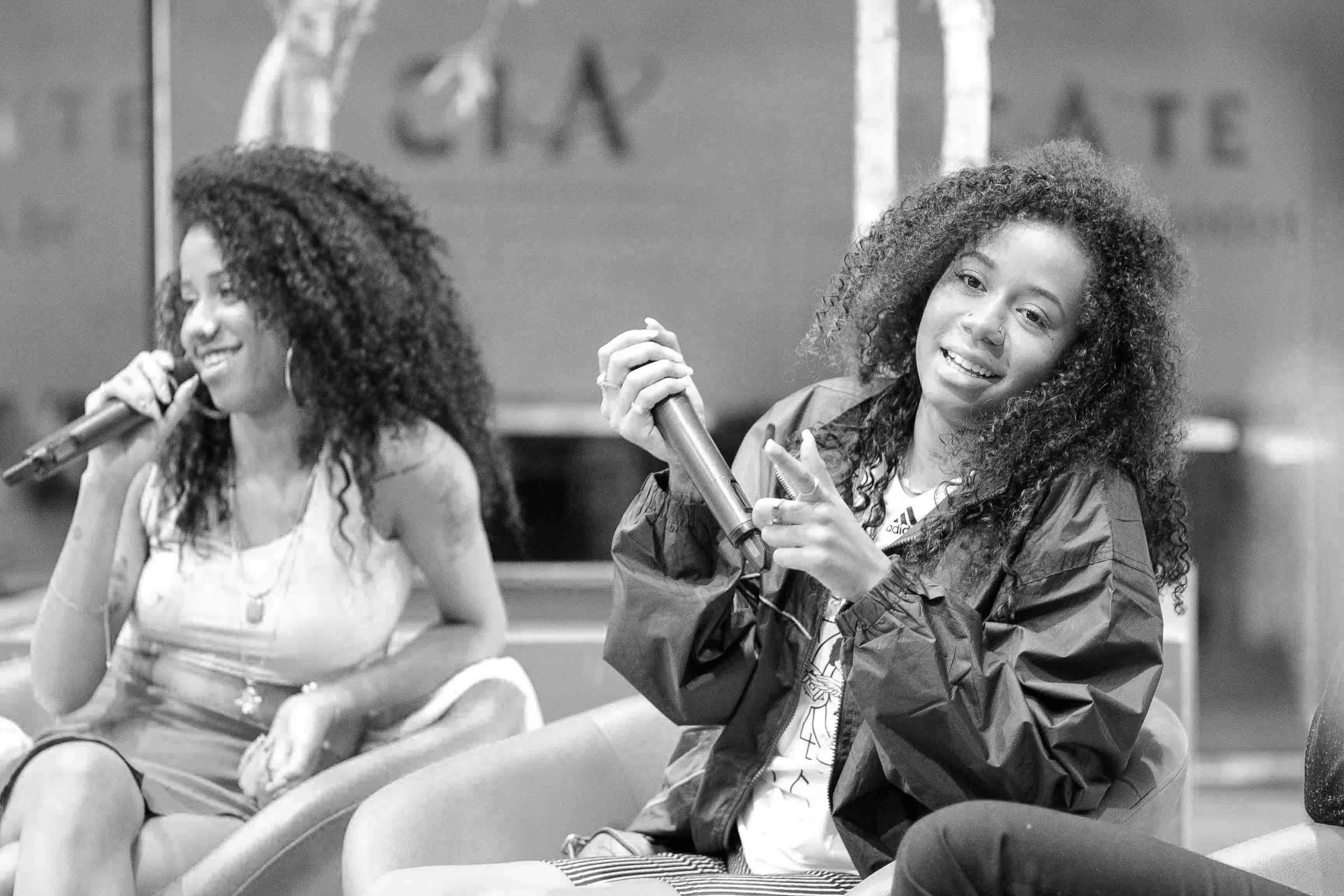 Two speakers laughing during a panel discussion on stage.