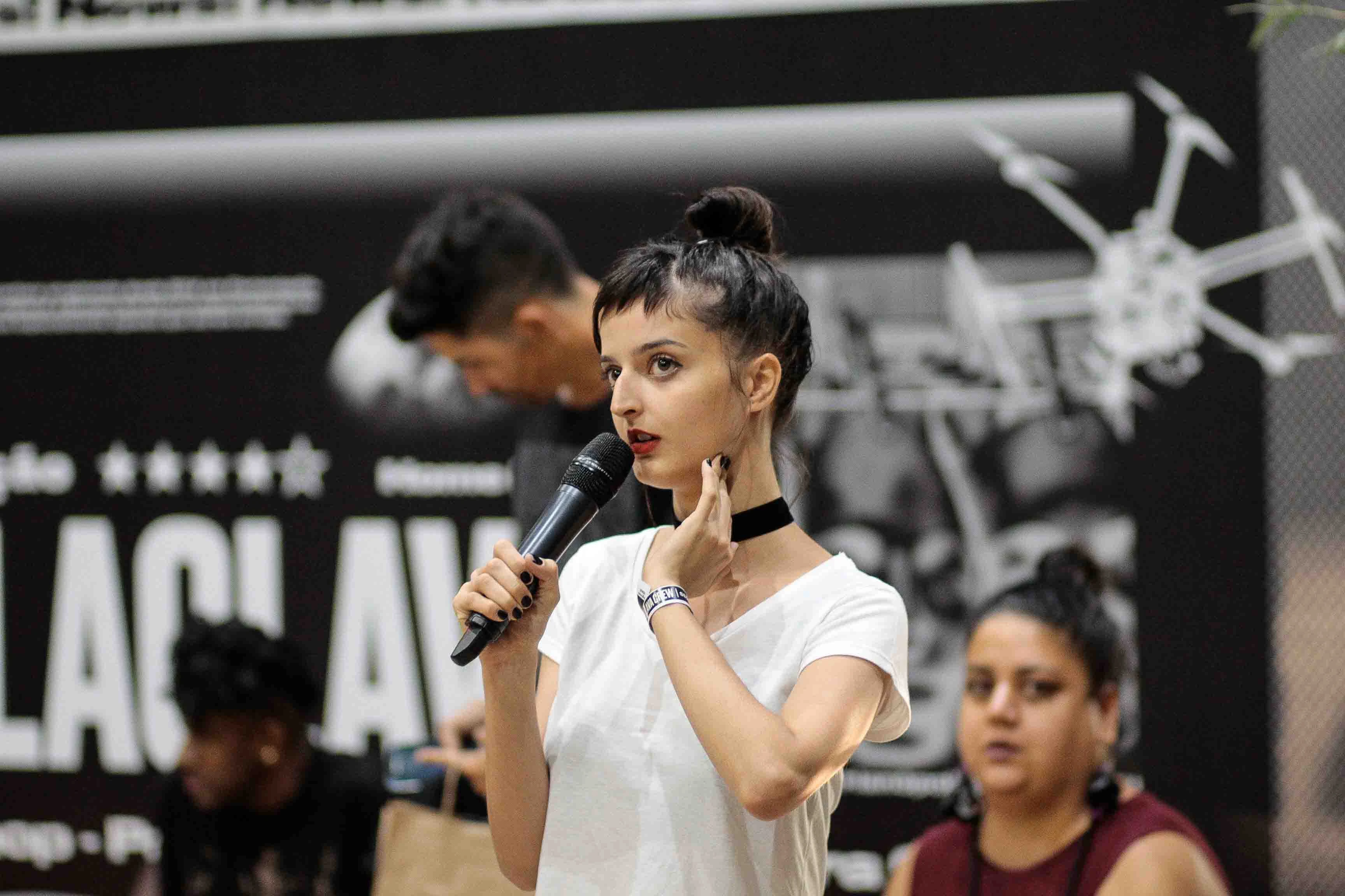 A speaker addressing the audience with a microphone at the fourth edition.